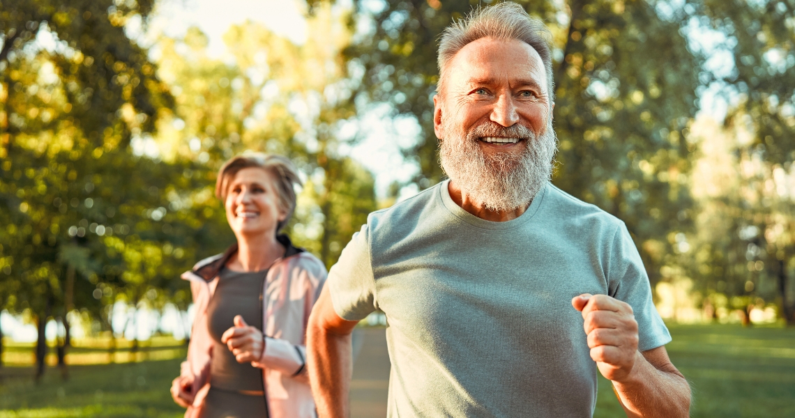 A couple smiling and running outdoors.