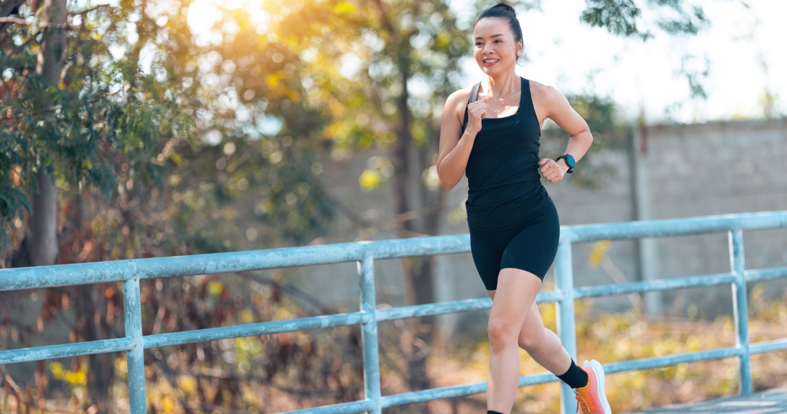 A woman in black workout attire jogging outdoors.