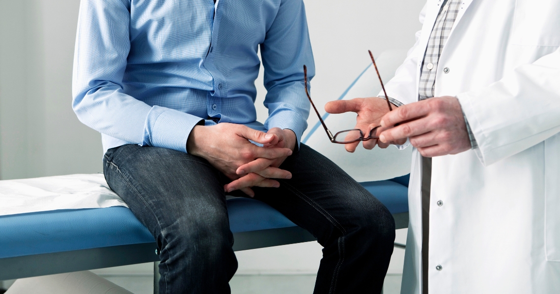 A male patient sitting next to a provider on an examination table.