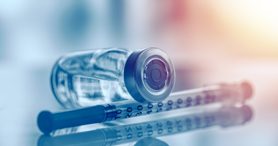 A vial laid on its side on-top of a syringe.