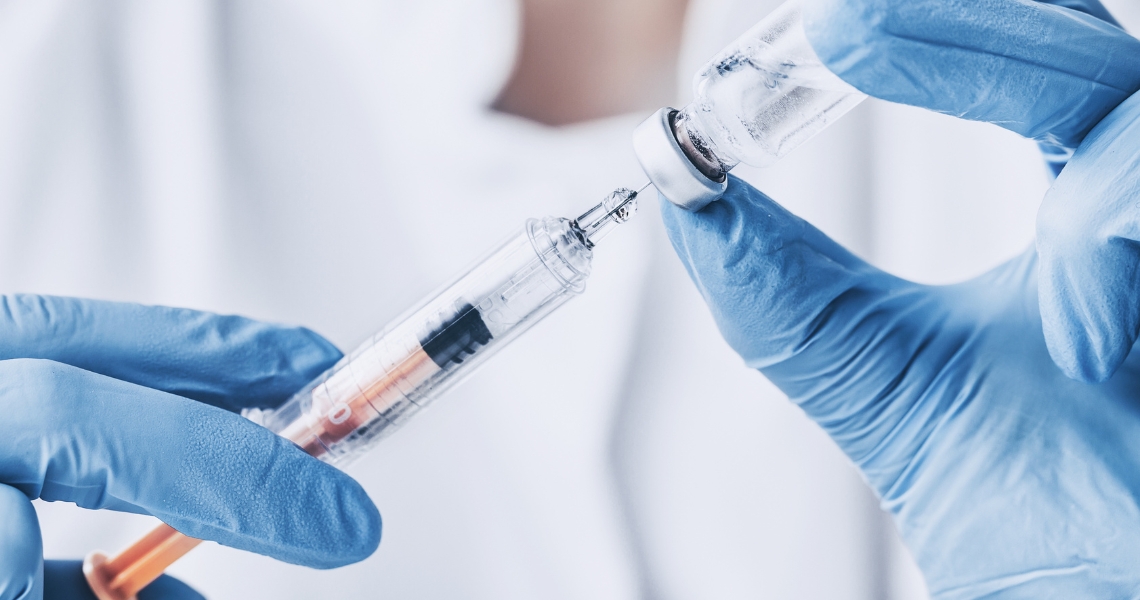 Gloved hands handling a syringe.