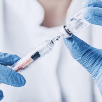 Gloved hands handling a syringe.