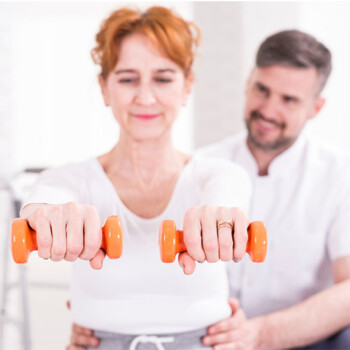 White background with woman holding hand weights and doctor behind her.