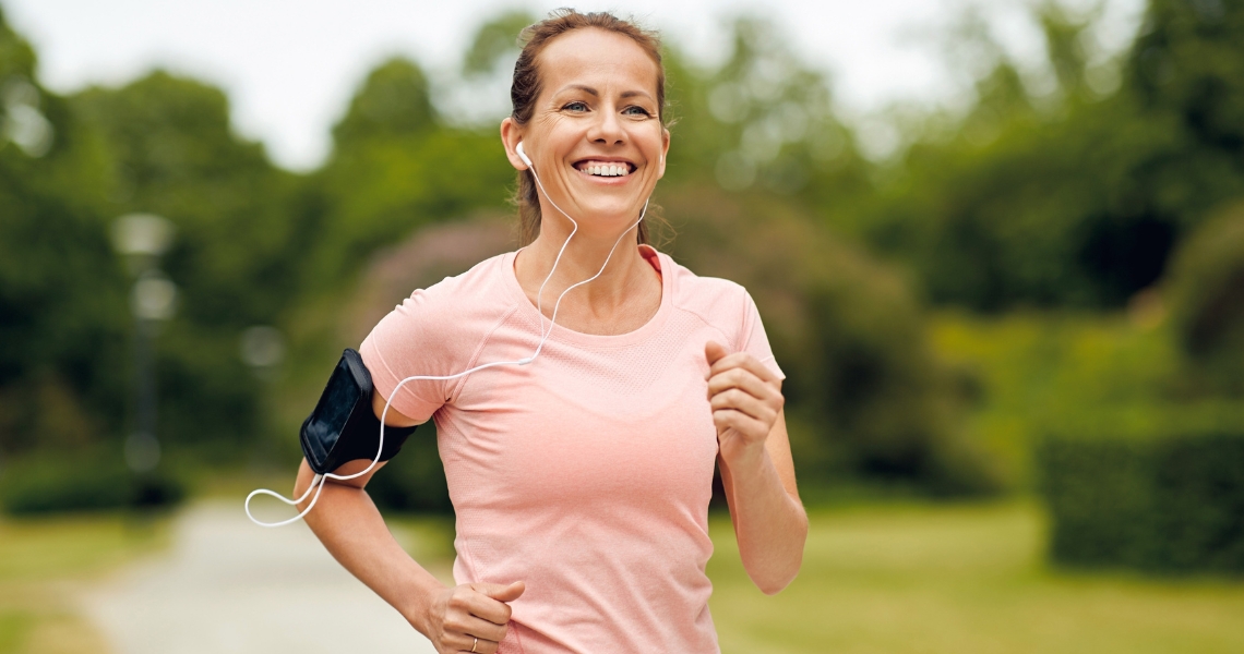 A woman in a light pink shirt running outdoors.