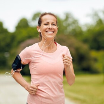 A woman in a light pink shirt running outdoors.