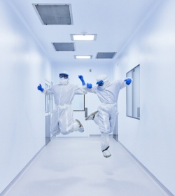 Two people in full PPE jumping in hallway.