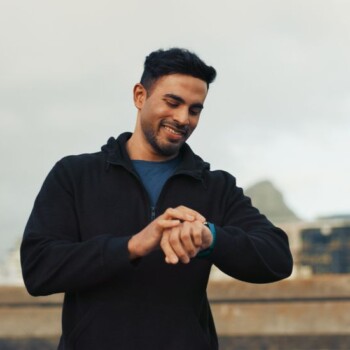 A man outdoors checking his watch.