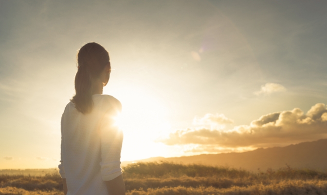 A woman looking into the sunset.