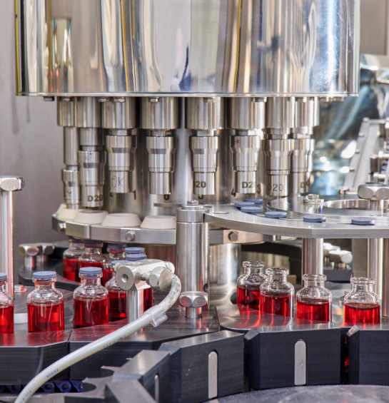 Vials of liquid getting lid put on in a machine.