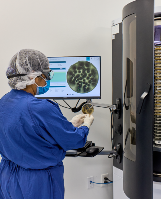 A worker looking a machine that shows a microscopic view.